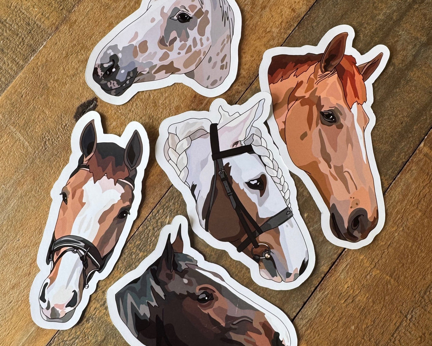Five horse head stickers on a wooden surface