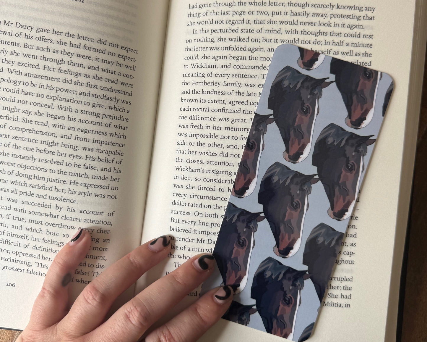 Open book with a hand holding a horse portrait bookmark