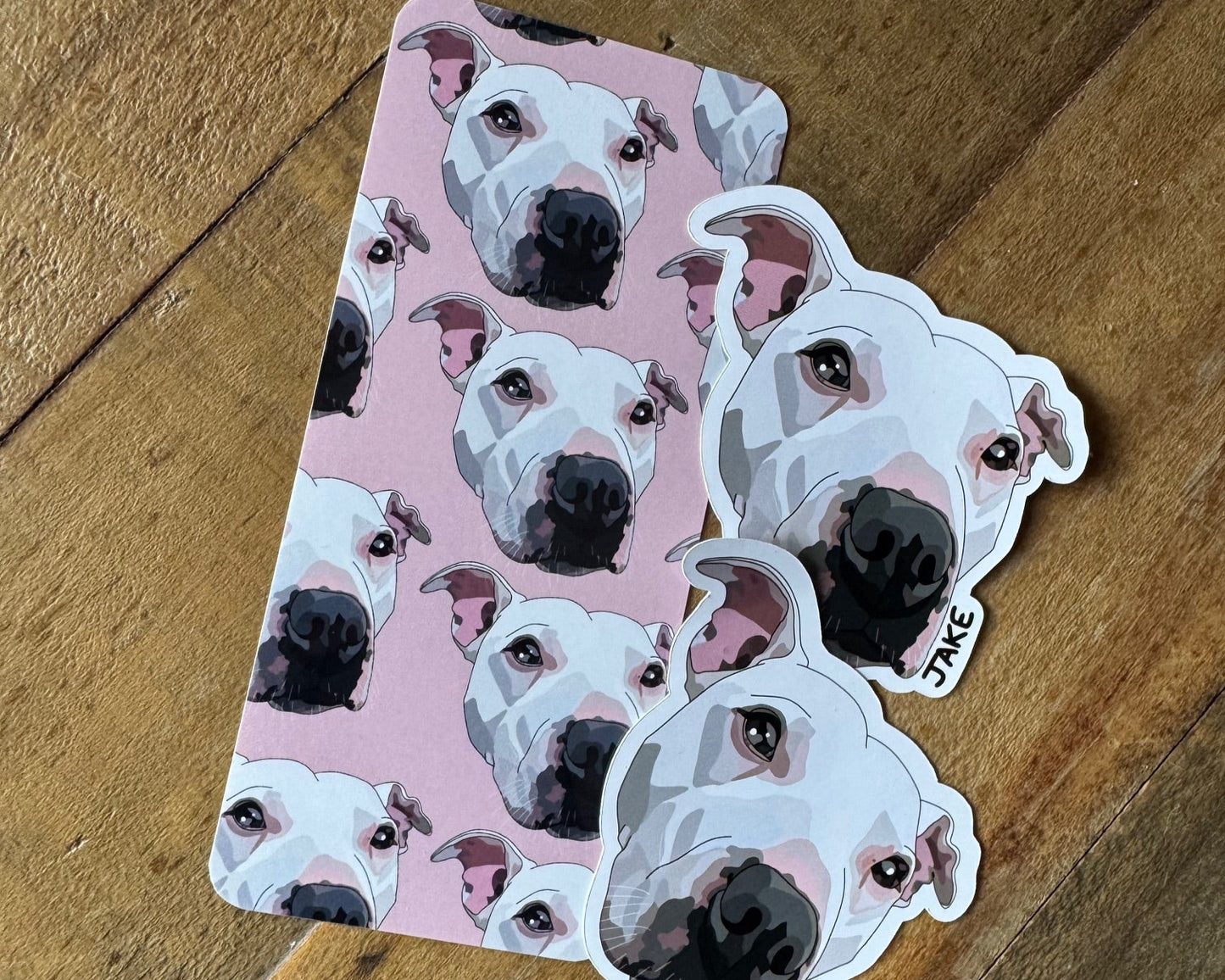 Sticker with dog pattern on a pink background, placed on a wooden surface.